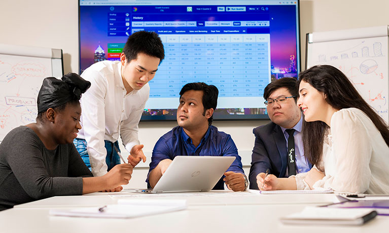 Five people around a table looking at a computer