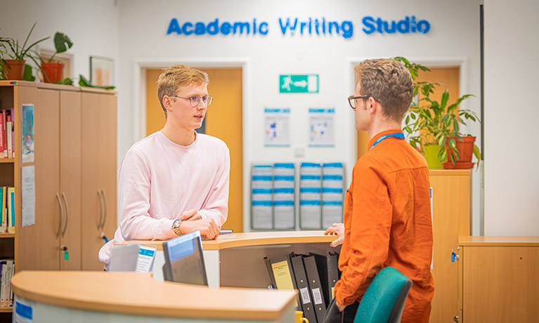 Reception of Academic Writing studio with two males chatting away