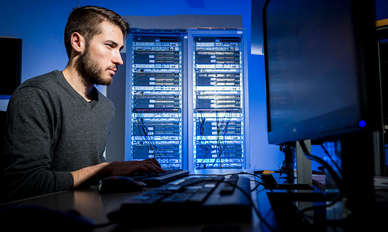 Man looking at monitor with servers in the background