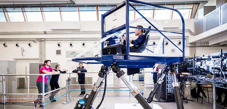 Student sat in simulator with others watching over
