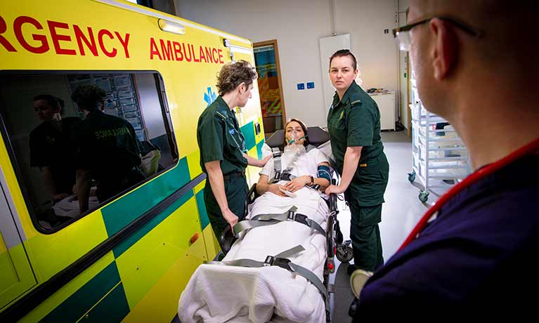 Students dressed as paramedics with a person on a stretcher