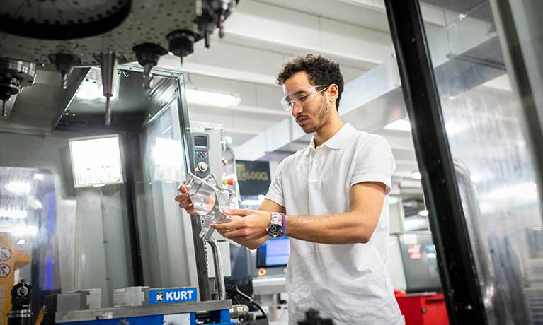 Man inside factory with a piece of equipment in his hands
