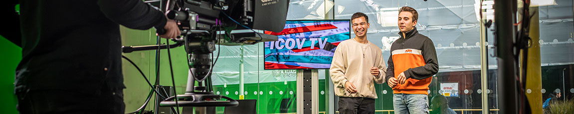 Two TV presenters in a studio with camera in view