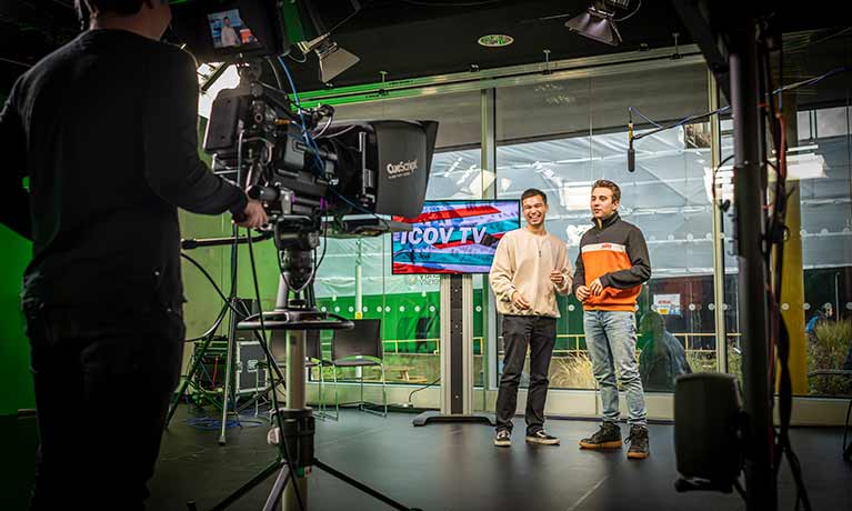Two TV presenters in a studio with camera in view