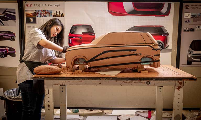 Student creating a large car model inside the clay studio 