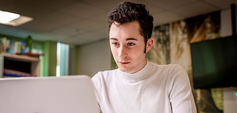 A student focusing intently on a laptop