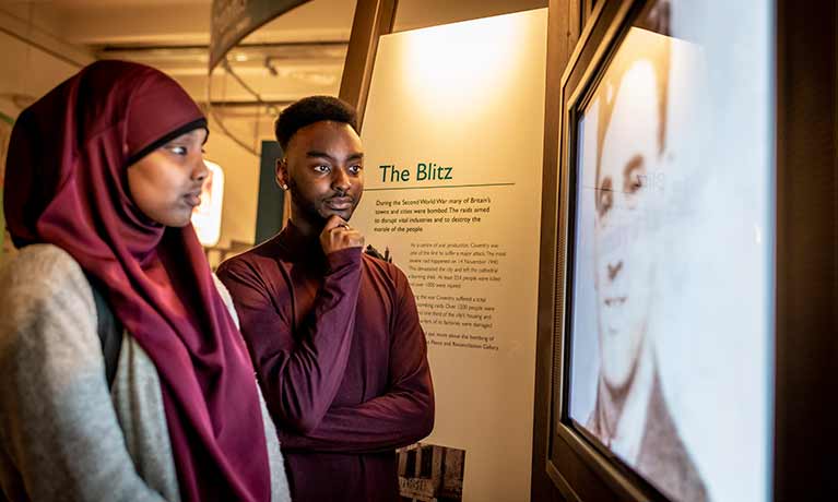 Man and woman looking at screen about the Blitz