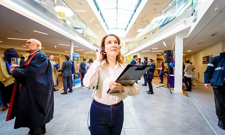 Lady with headset and clipboard looking upwards