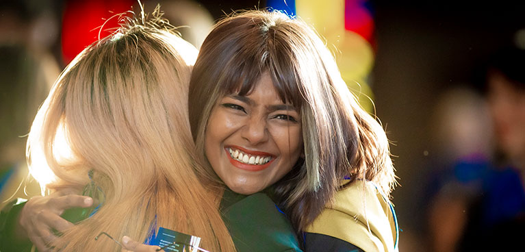 students hugging at graduation