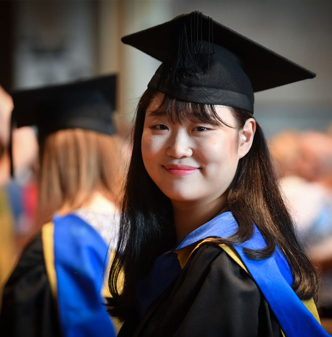 A female South Korean student in graduation gown and hat