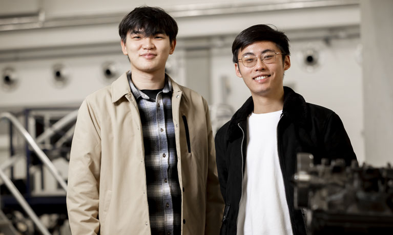 Two male South East Asian students in the metals workshop smiling at camera