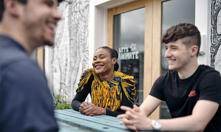 Three students talking and laughing with each other