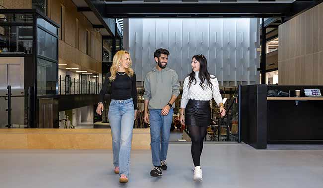3 students walking and chatting in the Delia Derbyshire building