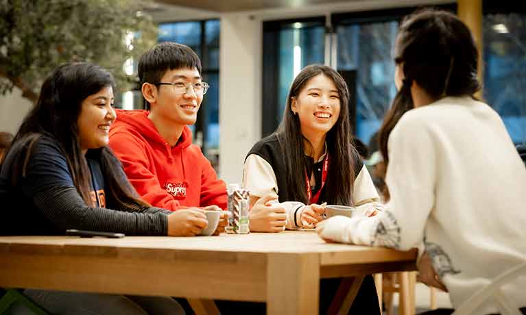 Group of international students sat at a table smiling