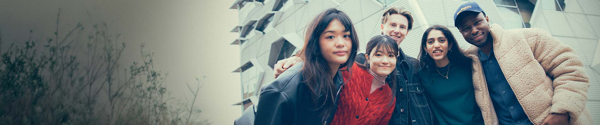 Group of students outside on campus looking down smiling