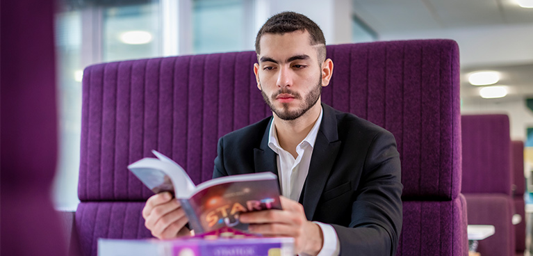 Male student sat down reading a book