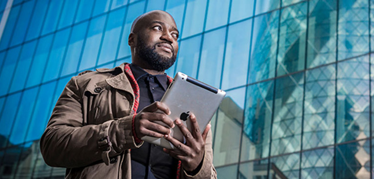 A student walking through London with a tablet