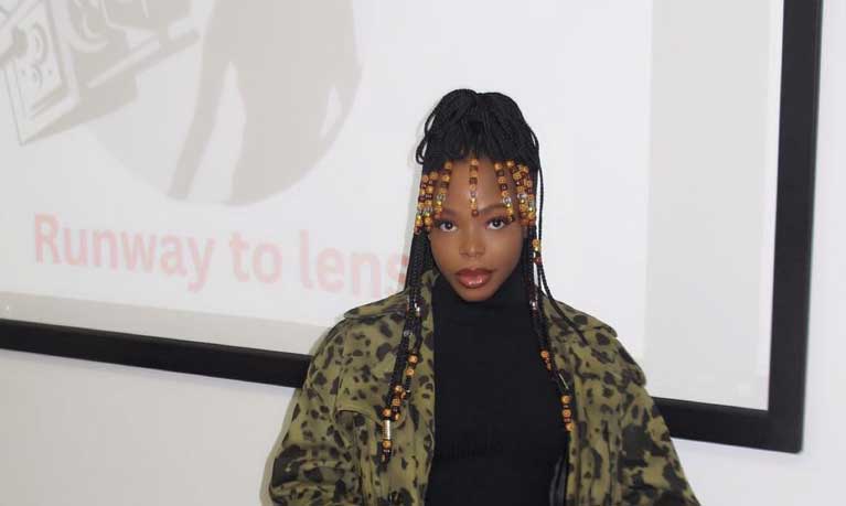International Fashion management student Laura Momodu in front of a screen