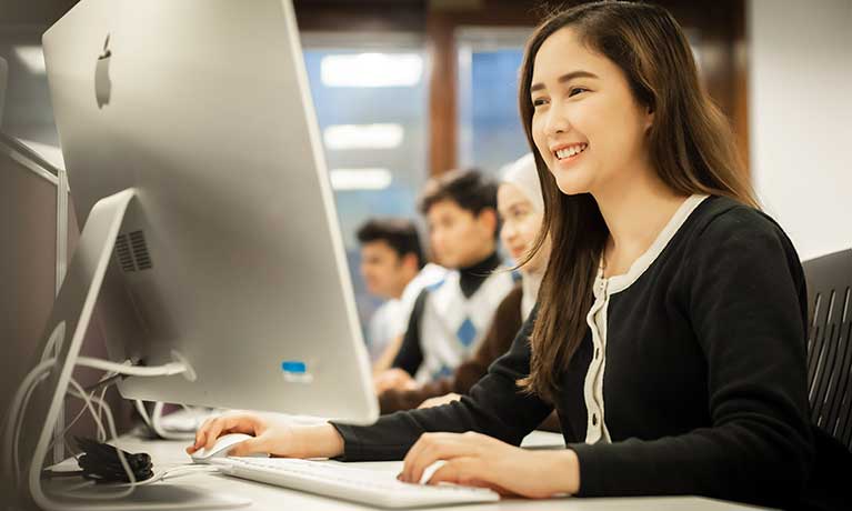 Student working at a computer with other students 