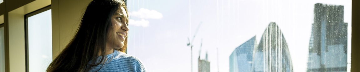 A student looking out of the window of the Coventry University London campus at the city skyline.