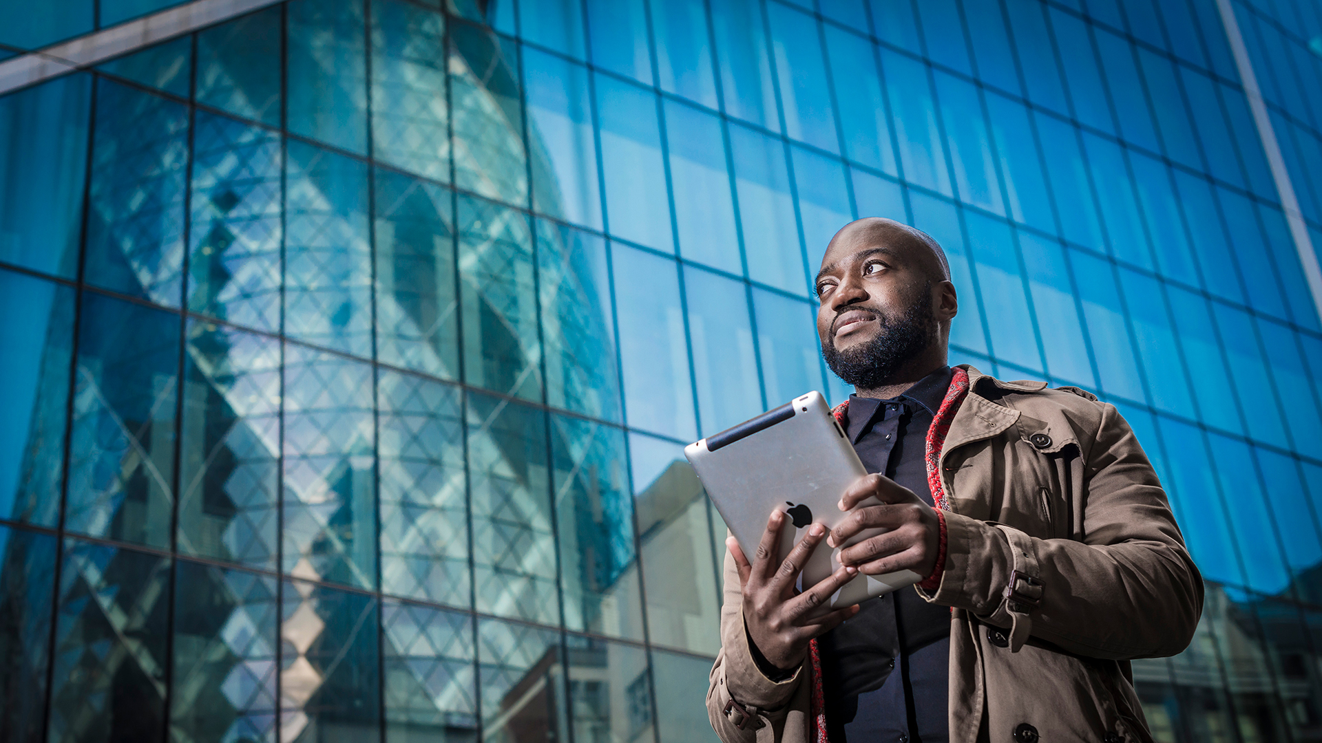 Tall man walking in front of a tall building in London