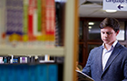 Young man wearing a grey suit and reading from a book