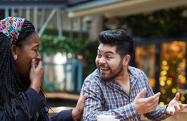 Two people laughing in an outdoor bar area
