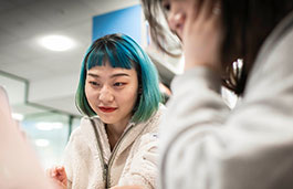 Young student with green hair talking to another female colleague