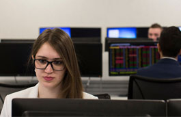 Student wearing glasses using a dual-screen desktop