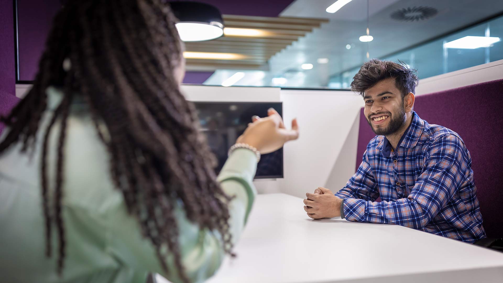 Young man sitting at a table smiling at a young woman 