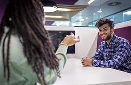 Young man sitting at a table smiling at a young woman 