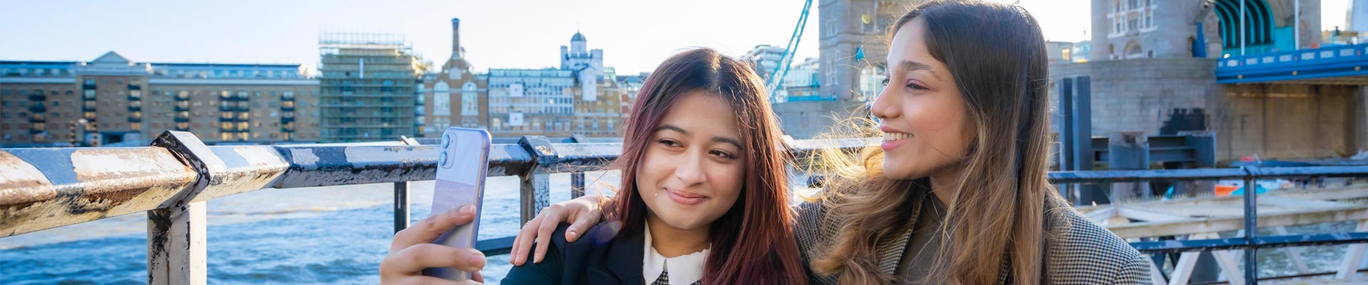 Two students taking a selfie in front of Tower Bridge in London.