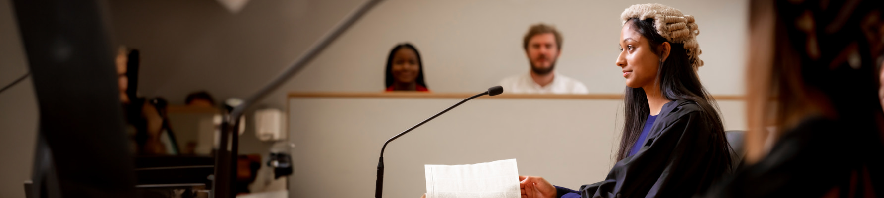 Female student wearing a judges wig in a mock court room.