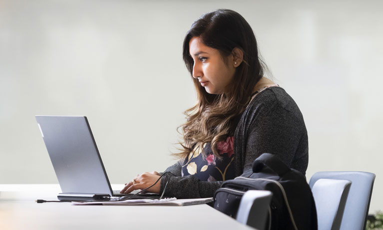 A girl sat at a desk on her laptop.