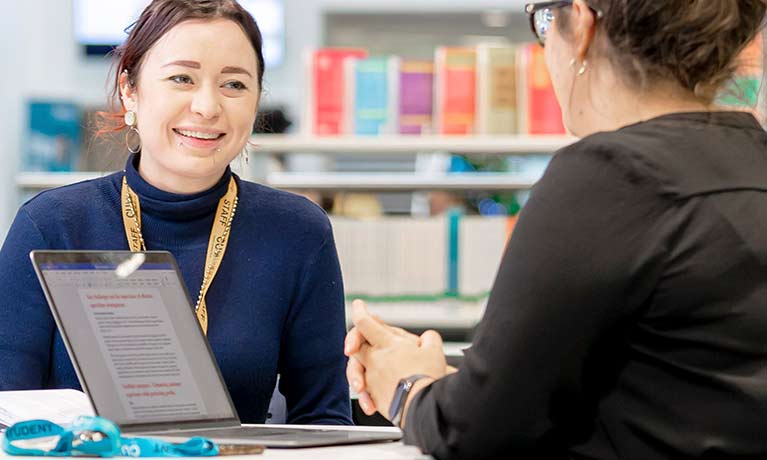 Staff and students discussing information on a laptop