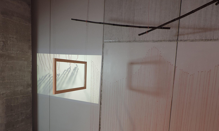 An art installation of  a frame hanging from the celling and the light causing shadows