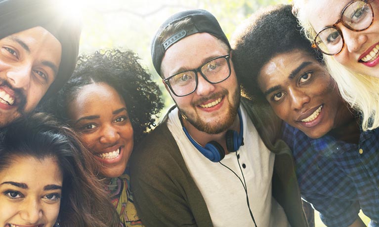 Group of diverse adults smiling outdoors for photoshoot