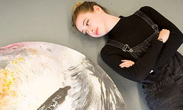 Student stood with arms folded, next to image of the world.