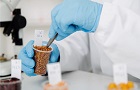 Hands wearing blue gloves in a lab holding a pot carrying out a test