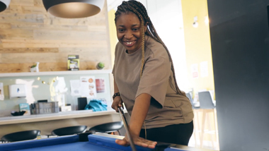 a student smiling, playing snooker