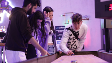 group of friends playing shuffle board in a bar
