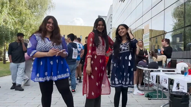 three students smiling outside of the welcome week fair