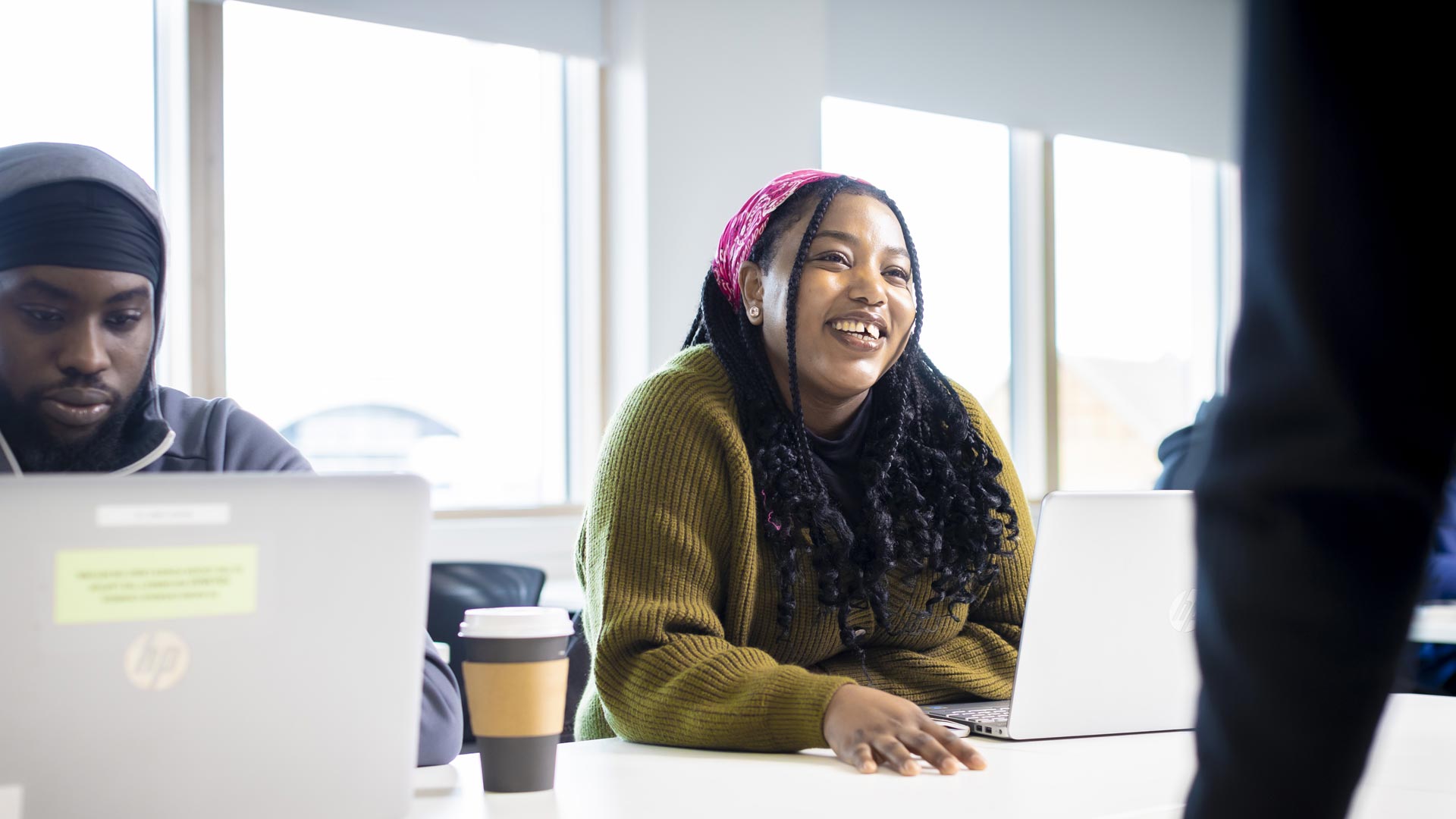 A marketing student smiling and looking up from her laptop.