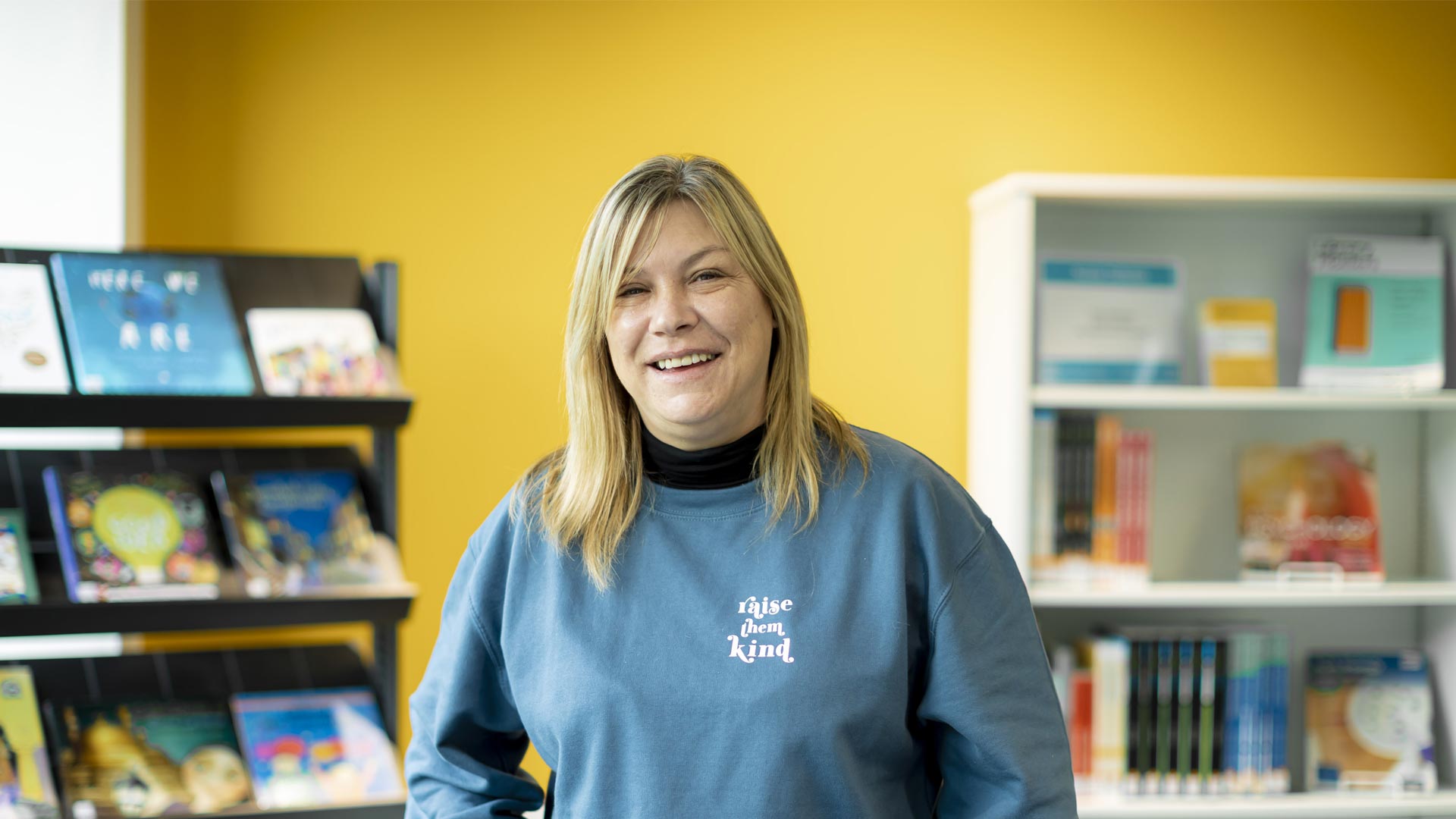Student in the library wearing a 'raise them kind' sweatshirt.