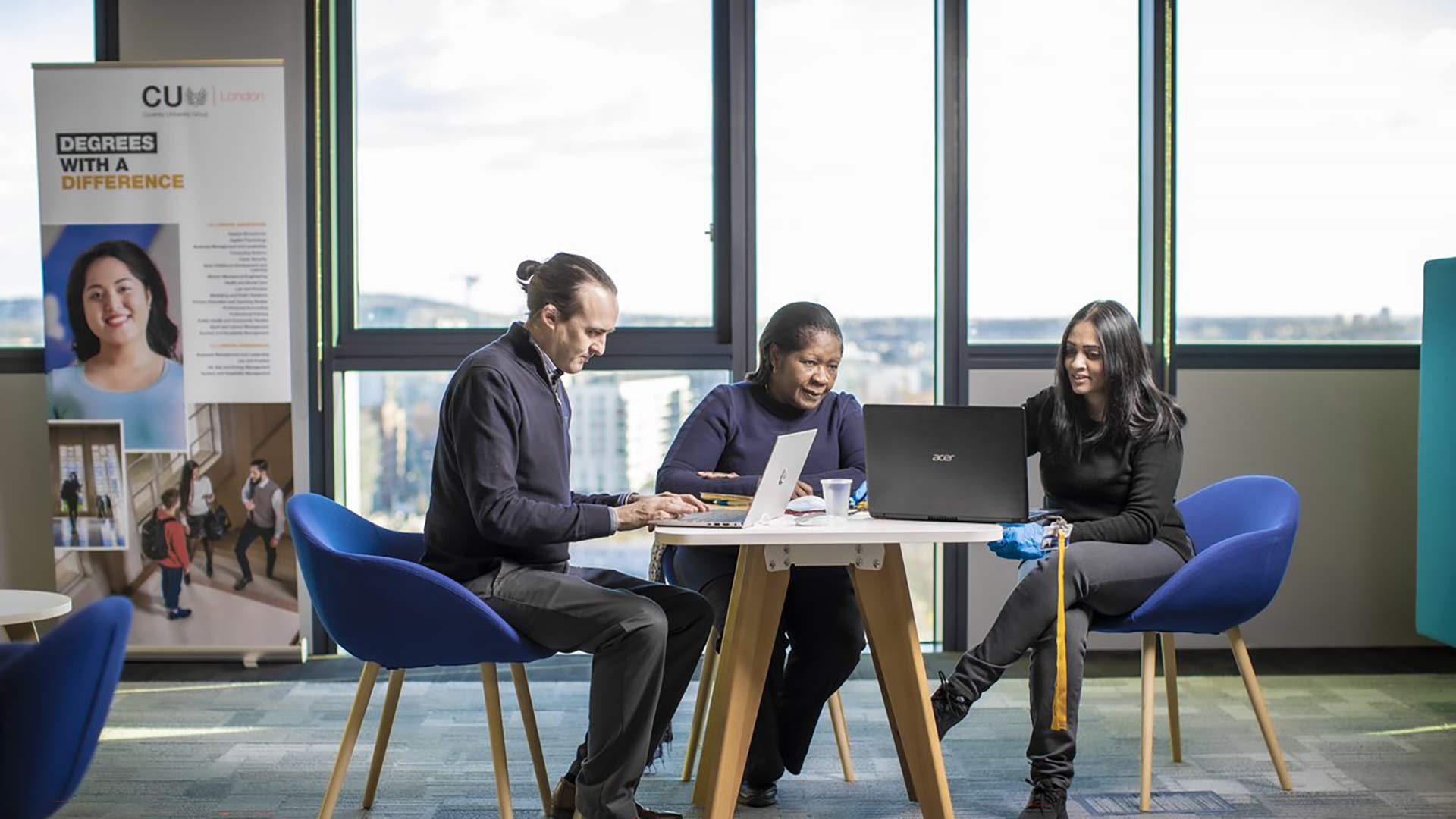 Three students at a table looking at laptops