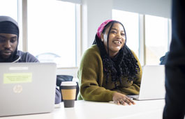 A marketing student smiling and looking up from her laptop.