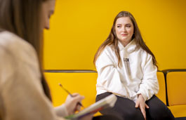 Applied Psychology student writing notes during a therapy session.