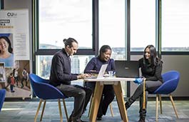 Three students at a table looking at laptops
