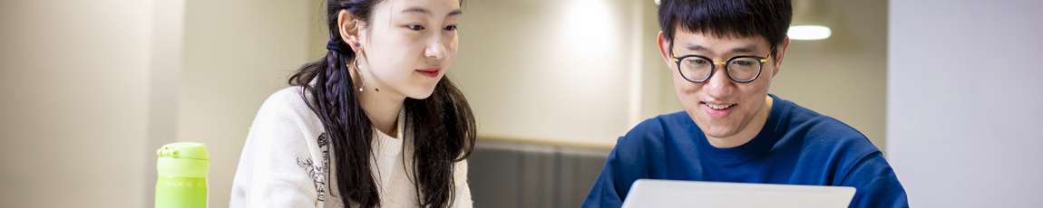 Male and female international student looking at a laptop screen