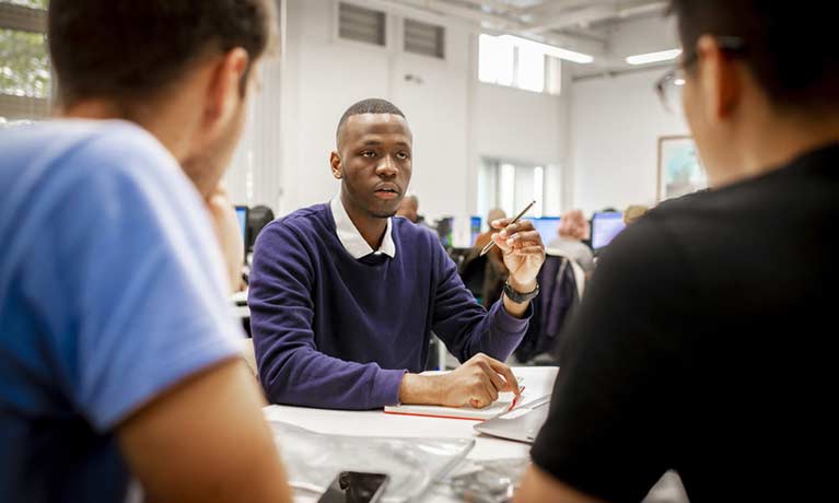 Students working at a table in a computer lab